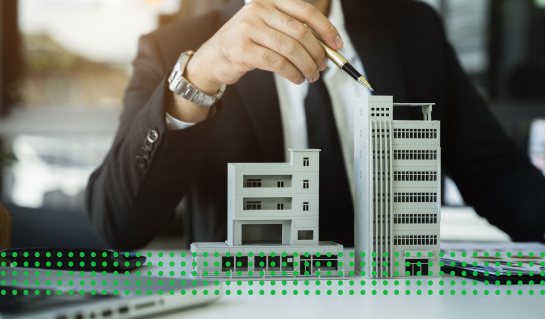 A COMMERCIAL BUSINESS LOAN - photo graphics man pointing a pen at building models