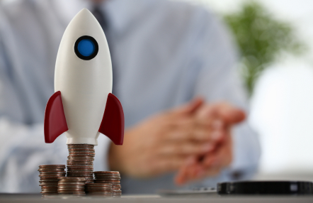 criteria for a startup loan - photo graphics small model of rocket on stacks of coins