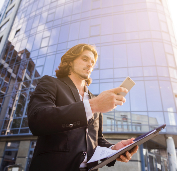 COMMERCIAL REAL ESTATE LOANS & EQUITY - photo graphics man holding phone and paper clip standing next to skyscrapers